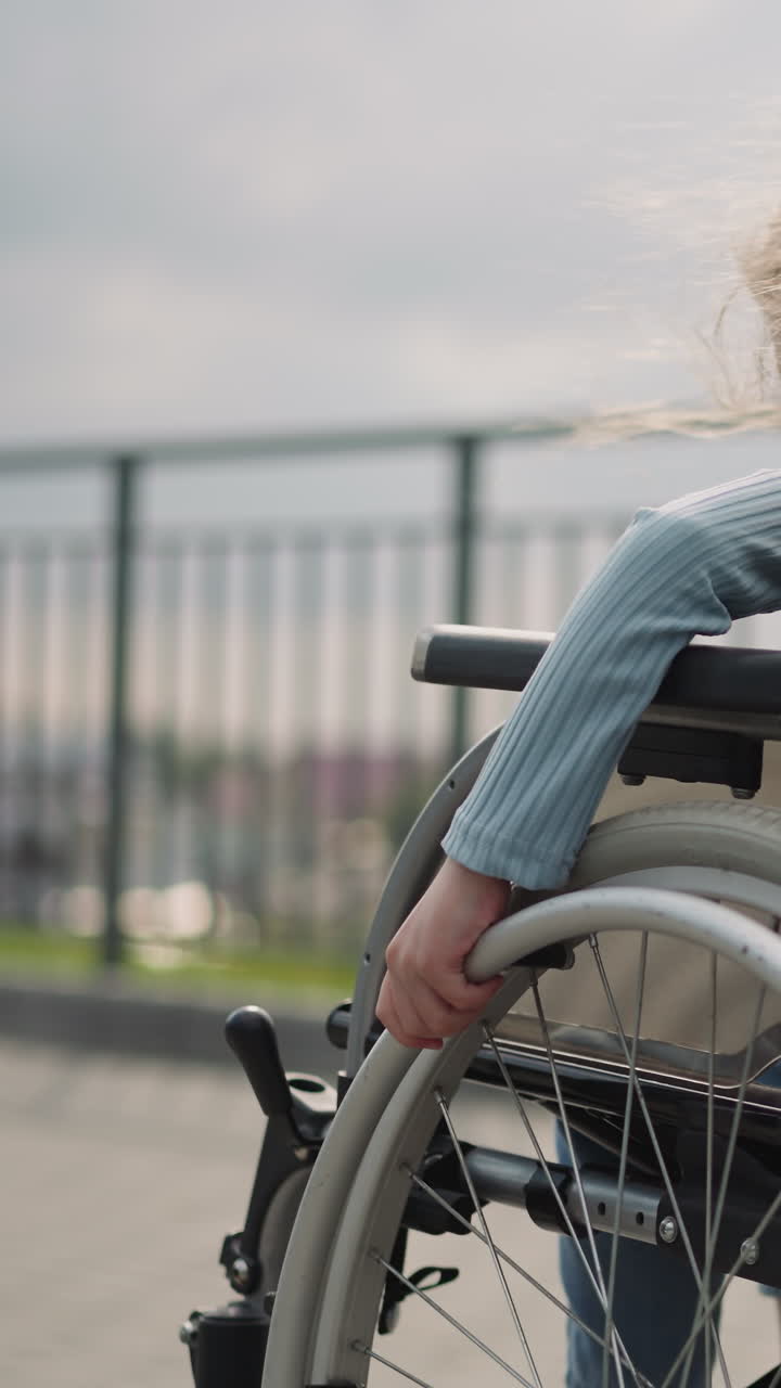 niña pequeña gira las ruedas de equipos médicos para moverse en el punto de vista de la ciudad. niña de escuela con condición de salud crónica controla la silla de ruedas de cerca