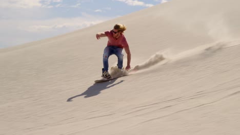 man sand boarding on the slope in desert 4k