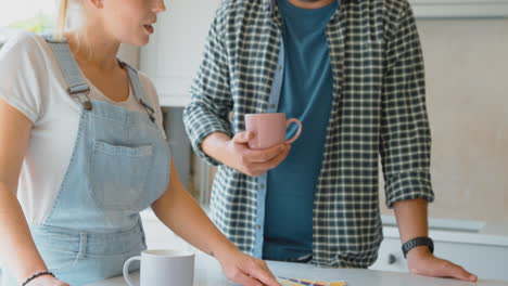 couple renovating kitchen at home looking at paint swatches on coffee break