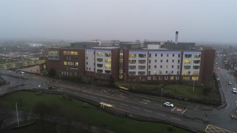 misty foggy hospital building uk town traffic aerial view low angle dolly right