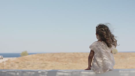 Little-lonely-girl-in-dress-sitting-and-enjoying-the-view-in-a-summer-day