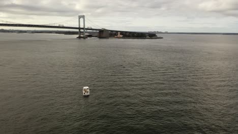 A-low-angle-view-of-a-single-white-boat-anchored-in-the-East-River,-near-the-Throgs-Neck-Bridge-in-NY