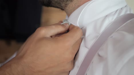 close up shot for man fixing tie of groom for wedding day