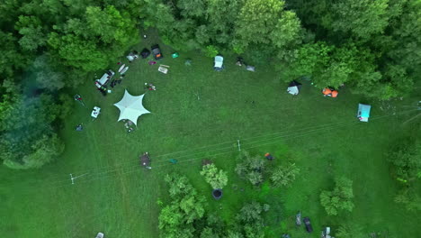 campers gather in a forest meadow for outdoor leisure - straight down aerial view