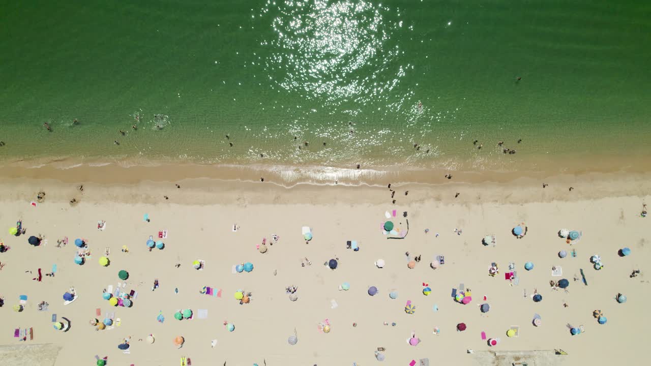 다채로운 파라솔과 포르투갈 세심브라의 해변에서 휴식을 취하는 사람들