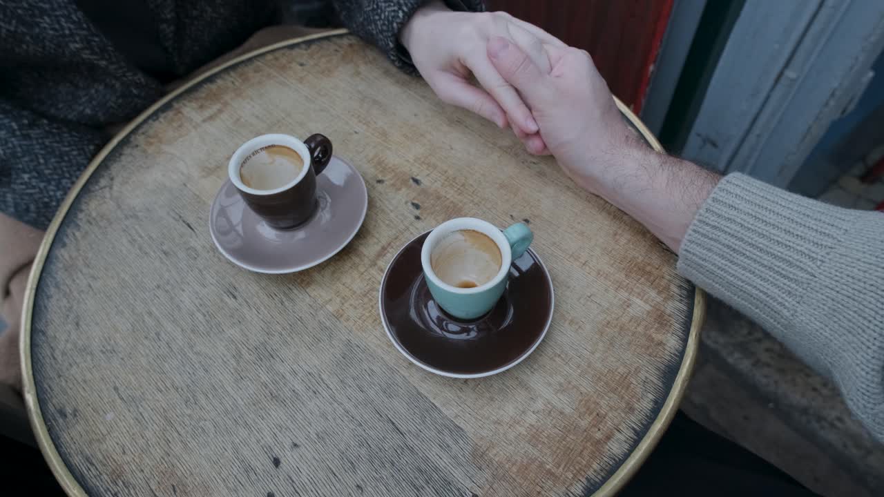 파리의 커피 테이블 위에서 서로 멀어지는 커플의 손