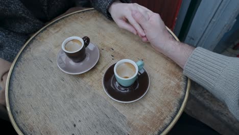 the hands of a couple moving apart over a coffee table in paris