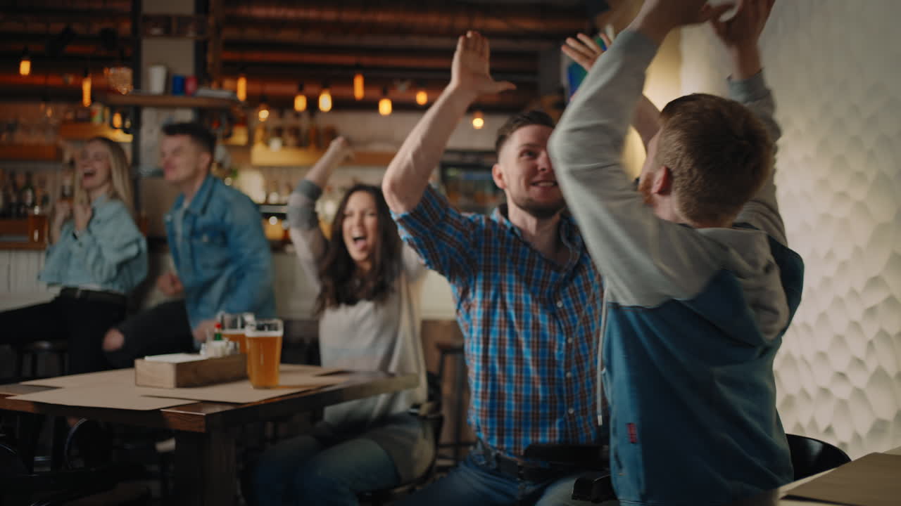 Friends are watching together emotionally watching football on TV in a bar and celebrating the victory of their team after scoring a goal. Watch hockey. The scored puck. Fans in the pub