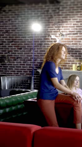 women relaxing and talking on a couch in a brick wall room