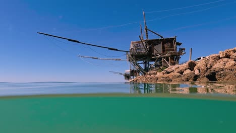 Split-underwater-view-of-trabocco-or-trabucco-at-Punta-Penna-beach-in-Costa-dei-Trabocchi-,-Abruzzo-in-Italy