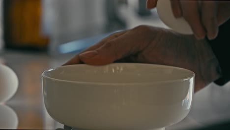 hombre rompiendo un huevo en el borde de un tazón blanco