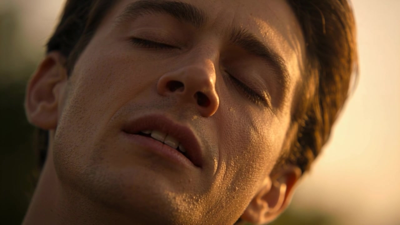 Uomo adulto che respira, chiudendo gli occhi e rilassando la mascella all'aperto mentre la calda luce del sole gli illumina il viso, sudando