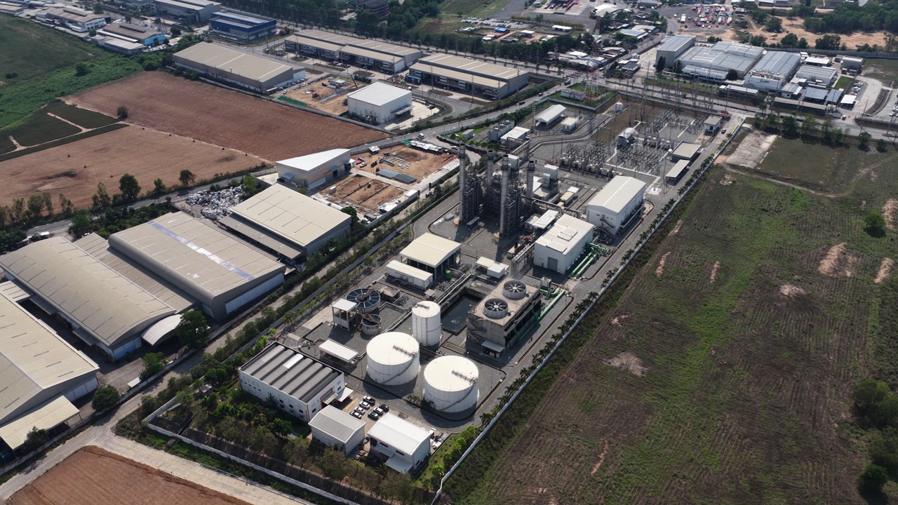 High aerial view showing a large industrial plant complex with storage tanks, pipelines, and manufacturing buildings, highlighting the scale of modern production and industrial infrastructure
