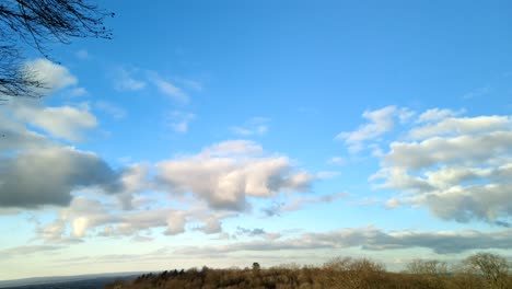 fast-moving clouds in time-lapse against a blue sky over a forest horizon