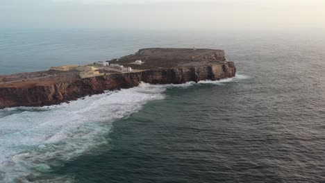 Cape-Sagres-Fortress-Portugal-and-lighthouse-on-top-of-the-eroding-Cape-Sagres-coast,-Aerial-approach-shot