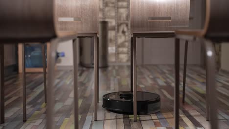 robot aspirador limpia entre las sillas en el comedor