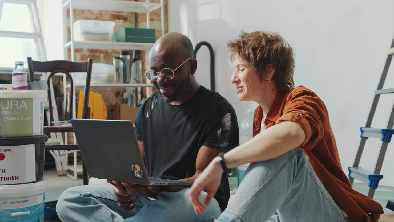Couple Browsing the Internet on Laptop and Talking in House under Renovation