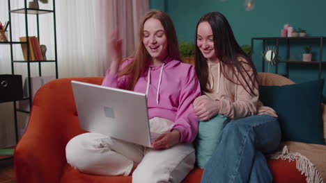 Young-teen-girls-friends-siblings-smiling-making-online-video-call-communication-on-laptop-notebook