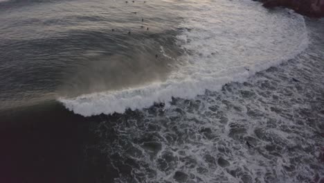 Luftdrohnenansicht-Einiger-Surfer,-Die-Fast-Nachts-Auf-Wellen-Reiten,-An-Der-Küste-Portugals