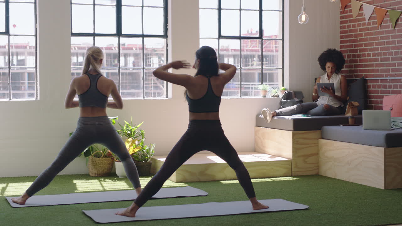 young business women practice yoga meditation together in office doing warrior pose enjoying mindfulness exercise relaxing on lunch break