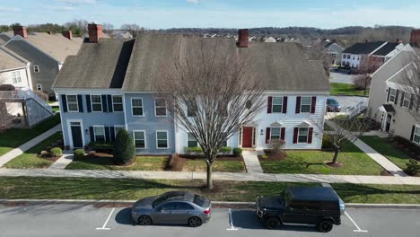 aerial trucking pan along multi unit homes in suburban neighborhood in fall