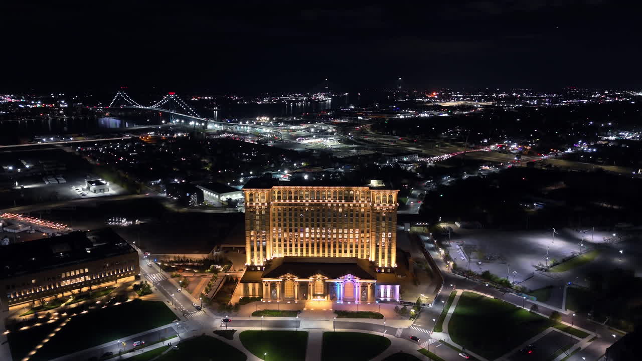 AERIAL: Michigan Central with Ambassador Bridge background, night in Detroit