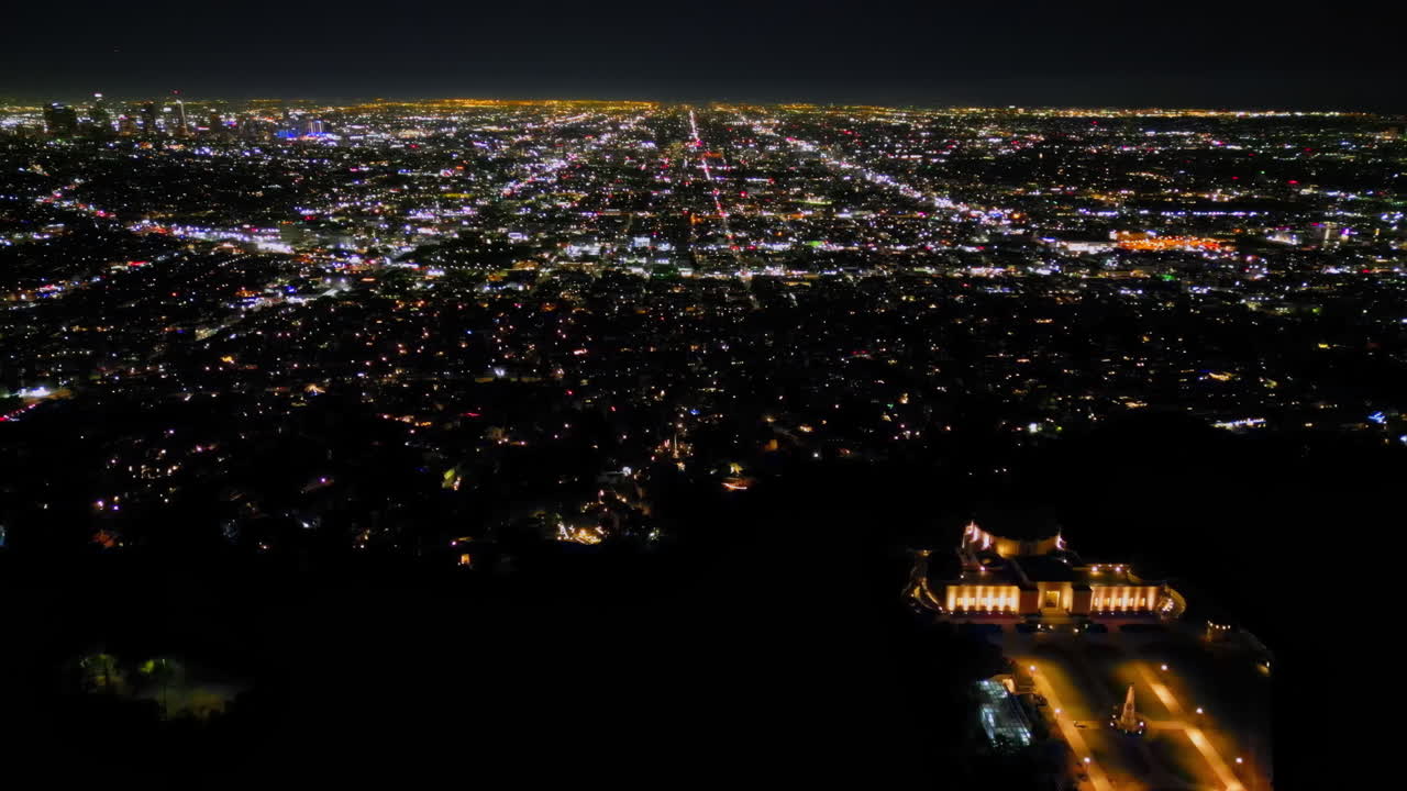 Aerial drone view of Los Angeles shining under the night sky, with the downtown skyline surrounded by glowing streets and traffic