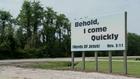 a large white sign quotes jesus along a rural roadway