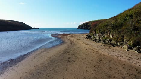 Aerial-POV-flying-over-Beach-in-Waterford,-Ireland-during-beautiful-day