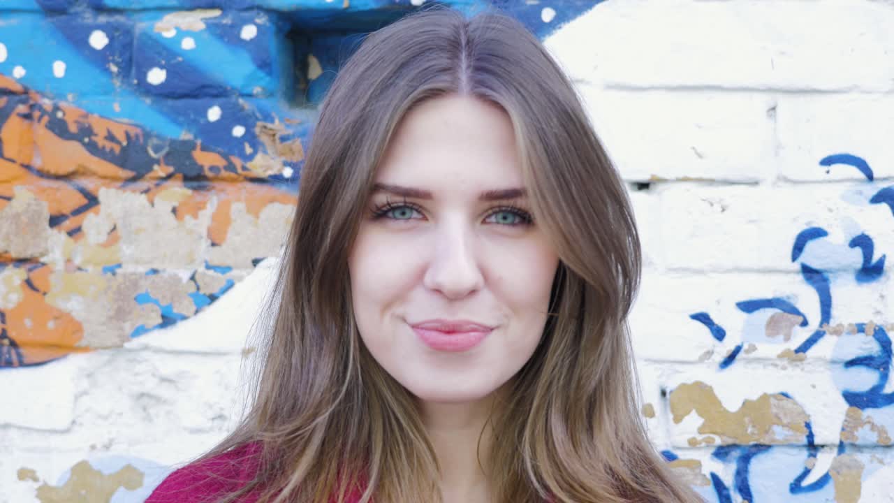 mujer sonriente frente a una pared de graffiti