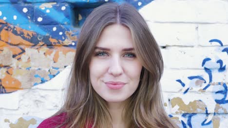 smiling woman in front of a graffiti wall