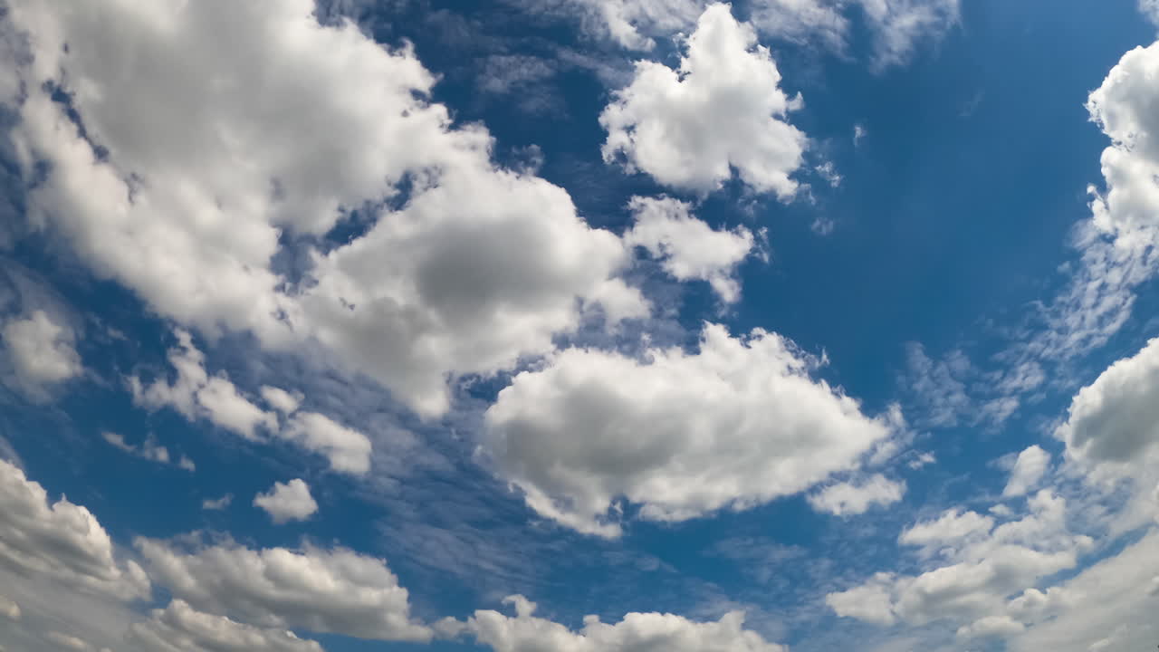 Diverse types of cloudscape in the atmosphere. Cumulus and stratus white clouds in the blue sky. Low angle view. Timelapse.