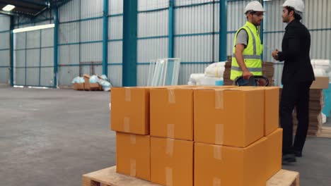 factory workers deliver boxes package on a pushing trolley in the warehouse .