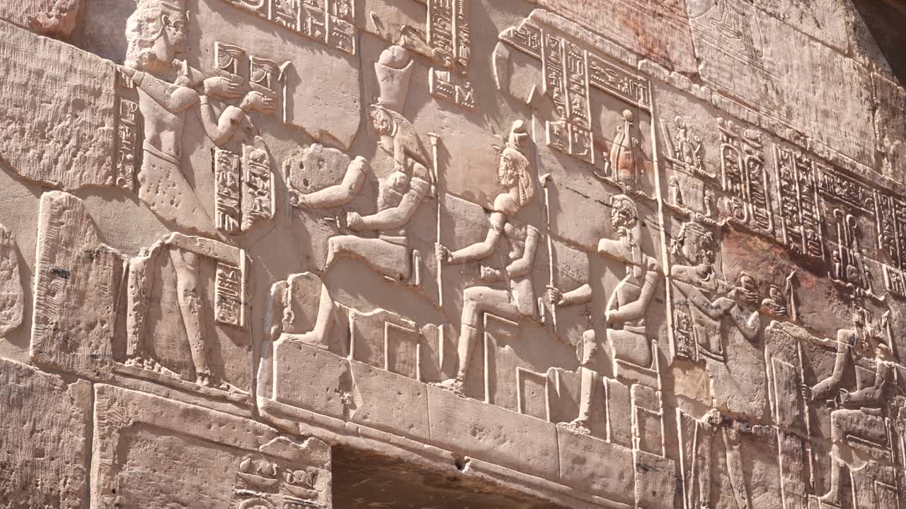Relief sculpture on ancient egyptian temple depicting Gods and Godessses