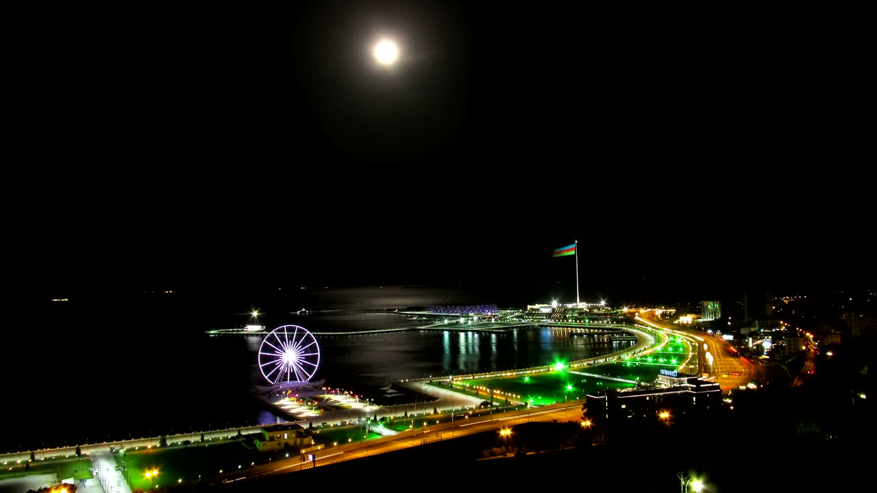 밤에 큰 도시의  풍경, 바다와 달의 경로를 배경으로 한 페리스, 도로의 교통.