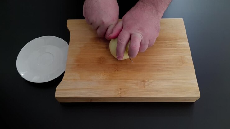 Primo piano su mani che tagliano una cipolla. Angolazione dall'alto