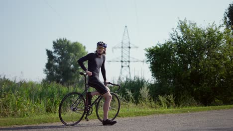 Retrato-De-Ciclista-En-La-Carretera-Vacía-Descansando-Sobre-Su-Bicicleta