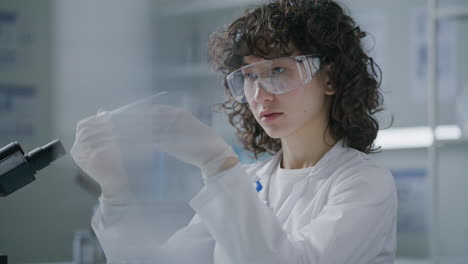 young female chemist transferring blue liquid into test tube during experiment
