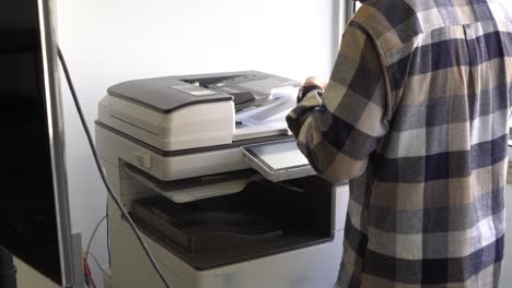 document printing concept: businessman arranging papers in front of laser printer control panel for copy scanner and document printing report chart chart in busy office