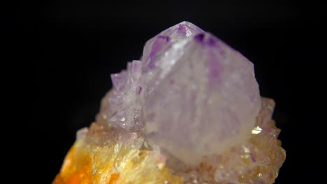 rotación sin problemas de un mineral (cuarzo ametrino) frente a un fondo negro