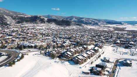 village houses and ski lodges covered in snow at wintertime in the town of steamboat springs, colorado with rocky mountains in background