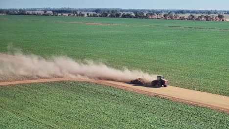 nubes de polvo salen de un tractor y un pequeño nivelador de carretera en el camino de la granja de tierra