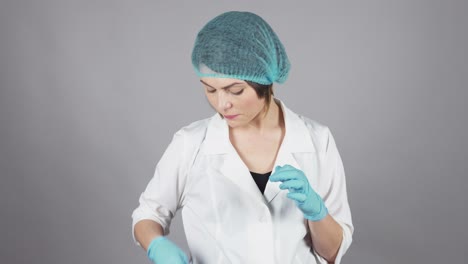 joven médica con guantes sosteniendo una jeringa y preparando una inyección aislada en un fondo gris. concepto de atención médica. filmado en 4k