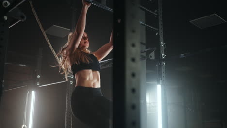 pull-up on sport bar in gym young beautiful woman is doing physical exercises in sport center