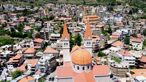 dome and spires of saint saba cathedral with bsharri town on a sunny day in lebanon