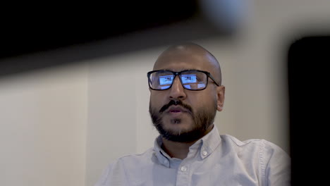 an abstract shot of a corporate employee frustrated as he attempts to find the information for his report, the tint on his glasses creating a clear reflection of the computer screen he is working on