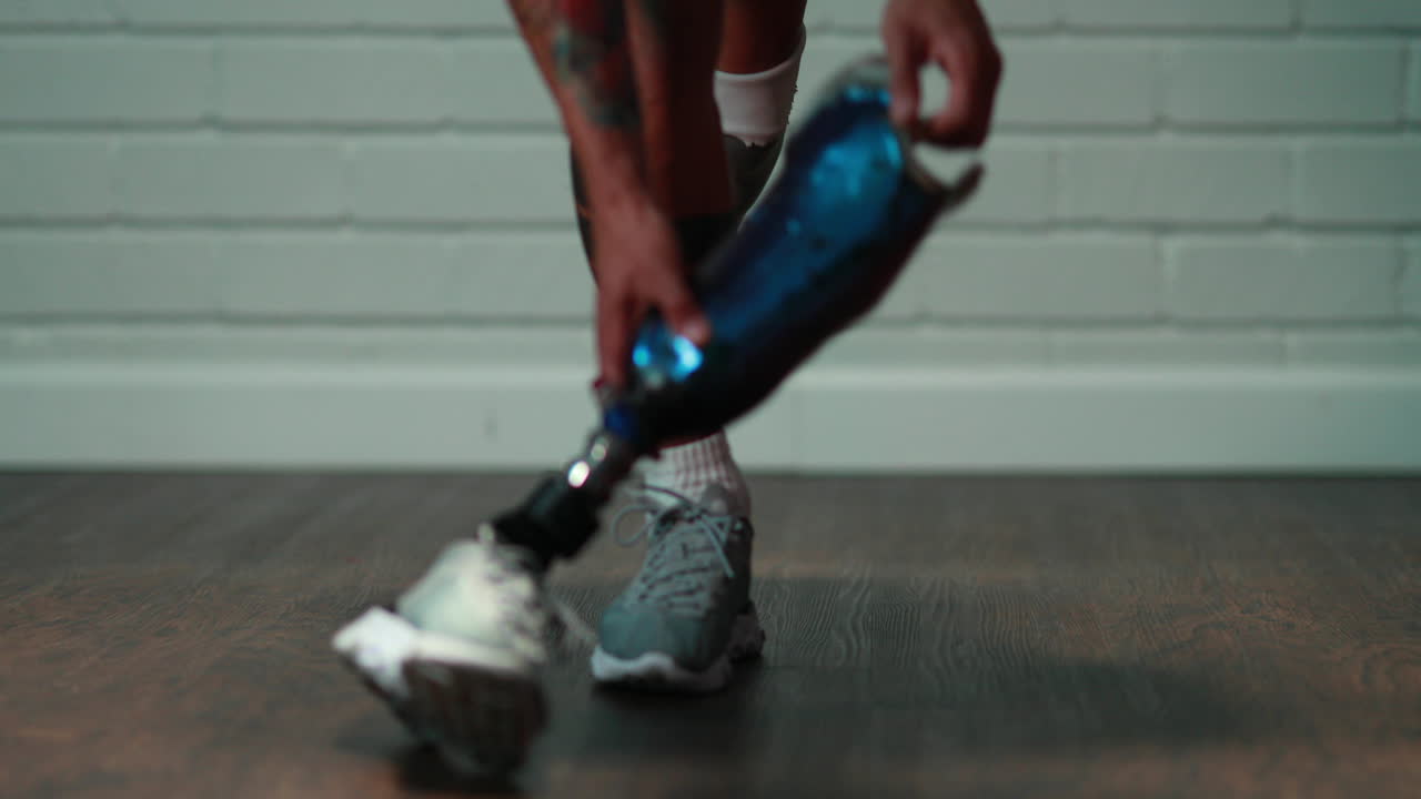 el hombre atlético se inclina para recoger y se pone una pierna prostética en cámara lenta