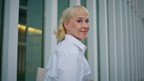 relaxed grandmother turning camera walking street in white shirt close up.