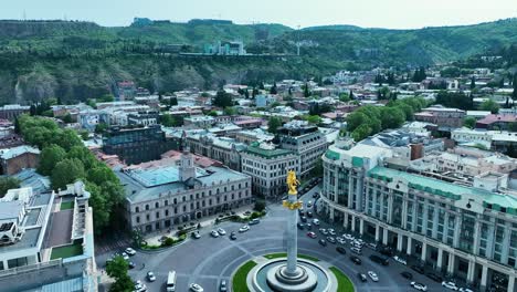 Toma-De-Drones-Para-La-Plaza-De-La-Libertad-En-Tbilisi,-Georgia,-Por-La-Tarde-Antes-De-La-Puesta-De-Sol-Al-Final-De-La-Primavera-Y-El-Comienzo-Del-Verano,-Cuando-Los-árboles-Se-Ven-Verdes.