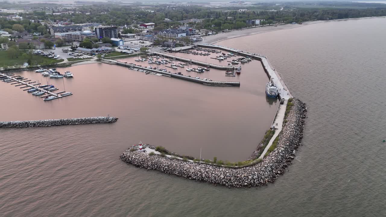 Dronebillede over Lake Winnipeg ved Gimli Havn, Manitoba, med udsigt mod byen, mens den langsomt roterer mod højre. Malerisk havnefront med marina og kystlinje i samfundet Ny Island.